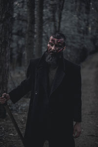 Man standing by tree in forest