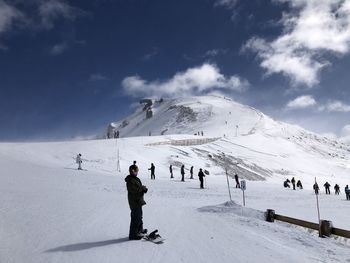 People skiing on snowcapped mountain against sky