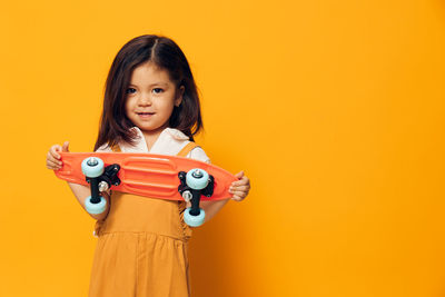 Portrait of young woman against yellow background