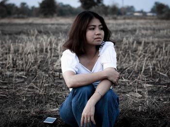 Beautiful young woman sitting on field