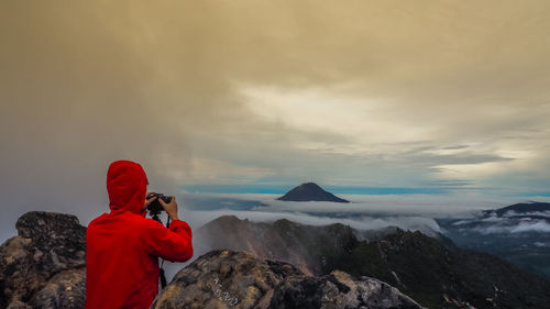 Rear view of woman photographing against sky during winter