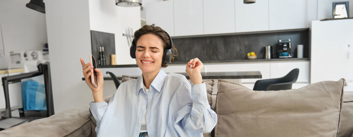 Young woman using mobile phone while sitting at home