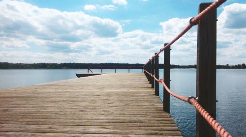 Pier on lake against cloudy sky