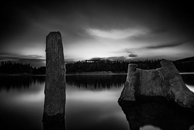 Wooden posts in lake against sky