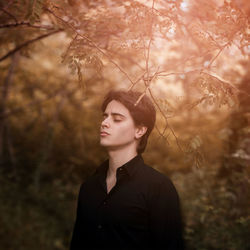 Young man looking away while standing on land