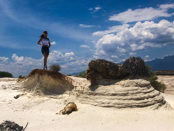 Woman standing on rocks against sky