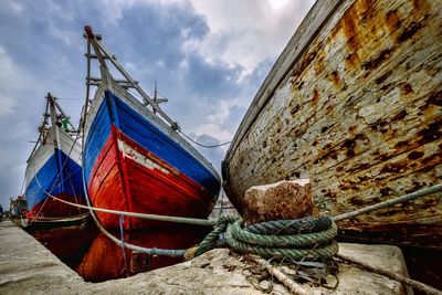 View of fishing boats moored at harbor against sky