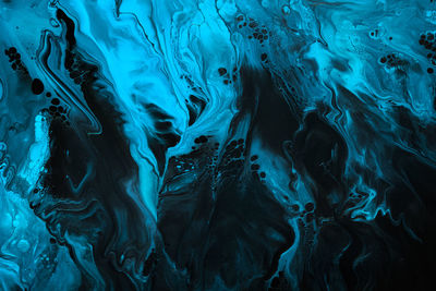 Fluid art. blue abstract wave swirls on black background. marble effect background or texture