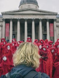 Rear view of woman standing against red building