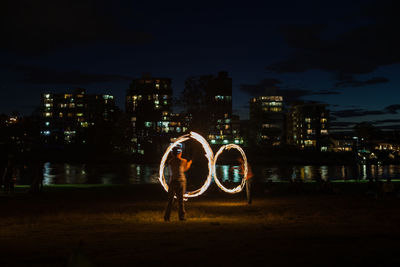 Rear view of woman standing against illuminated cityscape