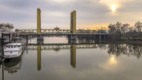 Reflection of factory on lake against sky during sunset