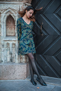 Woman looking down while leaning against wall