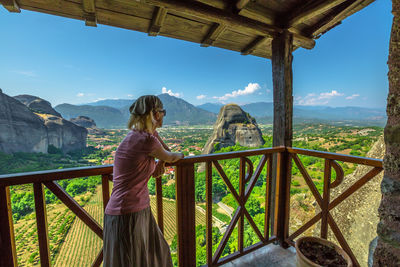 Side view of woman standing at observation point against landscape