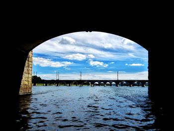Bridge over river against cloudy sky