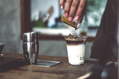 Midsection of person holding coffee cup on table