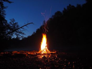 Bonfire on field against sky at night