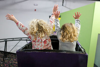 View from behind of two girls with hands up on rollercoaster