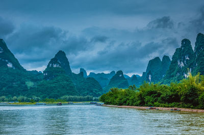 Scenic view of lake and mountains against dramatic sky