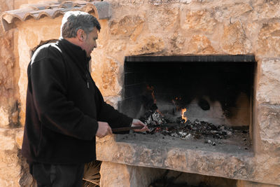 Rear view of man working at fireplace