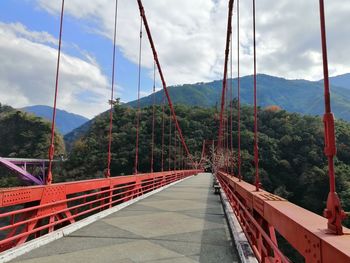 Footbridge amidst trees against sky