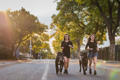 Full length of young woman with dog on road against trees