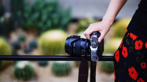 Close-up of woman holding camera on railing