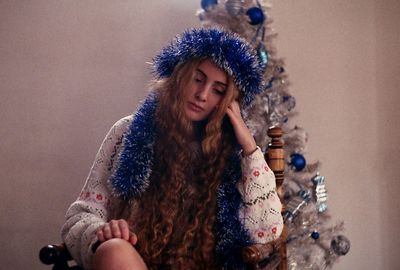 Young woman with blue tinsel while sitting at home