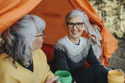 Two senior women sitting in front of tent at campsite