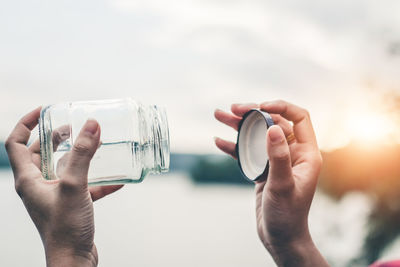 Close-up of hand holding glass against water