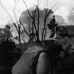 Low section of woman with bare tree against sky