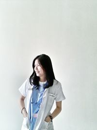 Smiling young woman standing against white background