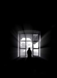 Silhouette woman sitting at window in darkroom