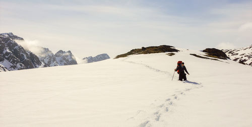 Man hiking on snowcapped mountain against sky