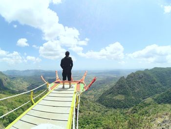 Rear view of man on mountain against sky