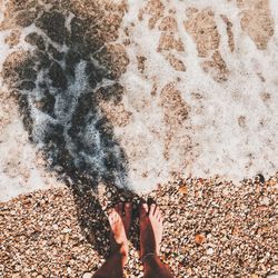 Low section of woman standing on sand