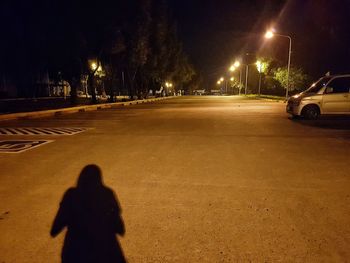 Shadow of person on illuminated street at night