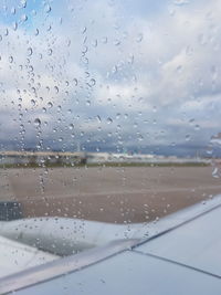 Water drops on glass window against sky