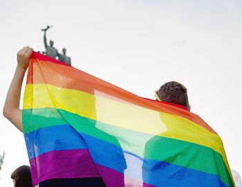 Rear view of man holding multi colored umbrella against clear sky