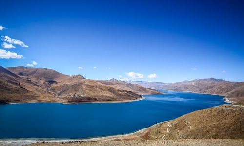 Panoramic view of lake and mountains against blue sky