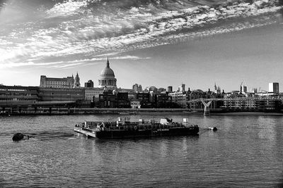 Boats in river by buildings against sky in city