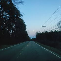 Road by trees against clear sky
