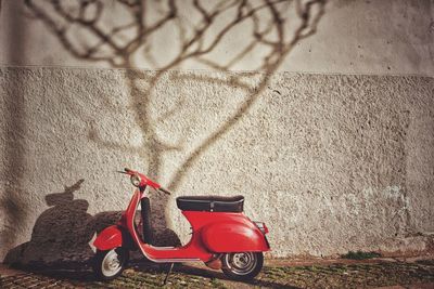 Motor scooter on footpath against wall