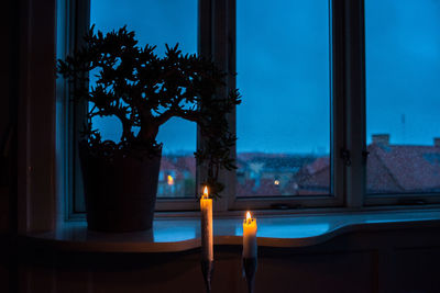 Close-up of illuminated candles on glass window