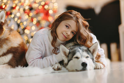 Cute girl hugging her husky friend on a christmas background