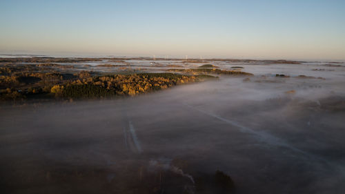 Scenic view of land against clear sky during sunset