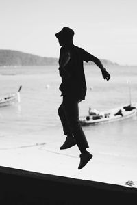 Low angle view of man jumping at beach against sky