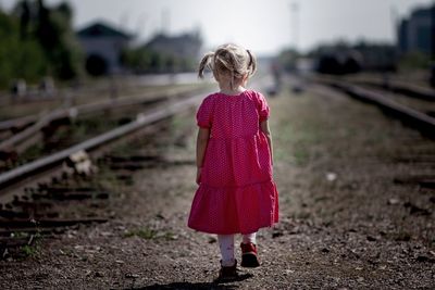 Back of caucasian child kid baby little girl going alone on railroad concept abandoned children