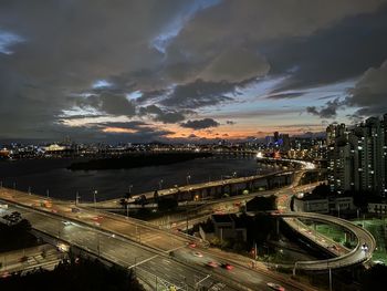 High angle view of illuminated cityscape against sky at sunset