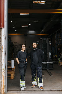 Portrait of multiracial male and female warehouse worker standing at doorway