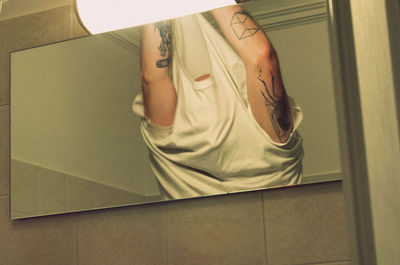 Reflection of man getting undressed in mirror at home